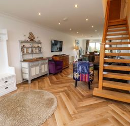 A living room with staircase and sofa at Farne Cottage Beadnell
