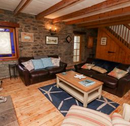 A living room with brown leather sofas and a wooden coffee table on a starfish patterned rug at Hares Form in Seahouses