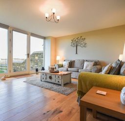 A living room with two sofas a coffee table and large glass doors at The Pepper Pot in Warkworth