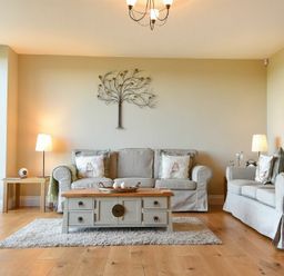 A living room with two sofas a coffee table two side tables with lamps and wall art at The Pepper Pot in Warkworth