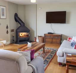 A living room with a wood stove television sofas and a wooden coffee table at The Mustard Pot in Acklington