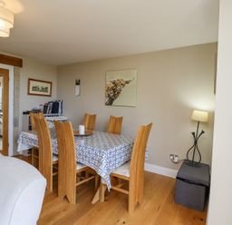 A dining room with a wooden table and six chairs a lamp and wall art at The Mustard Pot in Acklington