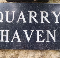 A close up of a black sign with white lettering that reads Quarry Haven