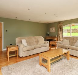 A living room with two beige sofas a wooden coffee table side table and a large window at Quarry Haven in Bamburgh