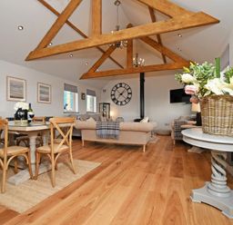 A living area with wooden dining table and chairs beige sofas wooden ceiling beams at The Hemmel Beadnell