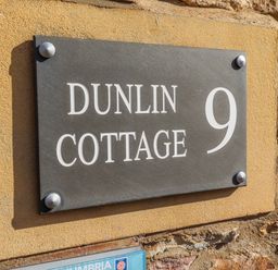 Nameplate displaying Dunlin Cottage 9 on a wall
