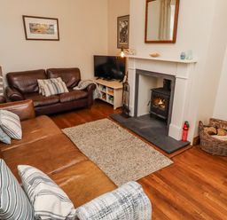 A living room with a sofa, television and fireplace at No9 Budle Sands in Bamburgh