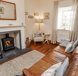 A living room with a fireplace and a sofa at No9 Budle Sands in Bamburgh