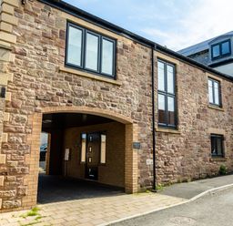 The exterior of a stone building with several black-framed windows and an arched entrance at Harbour Lights House in Seahouses