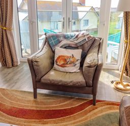 A living room with an armchair and blanket at Spindrifter in Beadnell