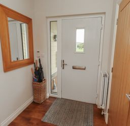 A hallway with a door and mirror at The Beach Hut in Beadnell