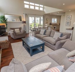 A living room with a sofa, coffee table, and armchairs at The Beach Hut in Beadnell
