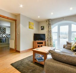 A living room with a sofa wooden coffee table television and an open doorway to a kitchen at East Havers in Alnwick
