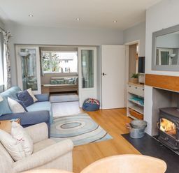 A living room with armchairs a wood burning stove a rug and a connecting smaller seating area at Manor Cottage in Embleton