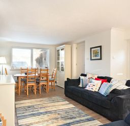 A living room with a blue sofa and wooden dining table with chairs at Stones Throw in Beadnell