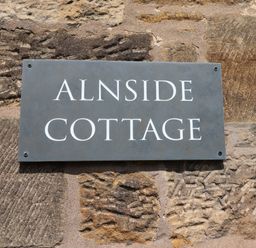 A sign reading Alnside Cottage mounted on a stone wall at Alnside Cottage in Alnmouth