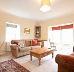 A living room with two sofas a wooden coffee table a TV and rocking chair at Dunrovin in Beadnell