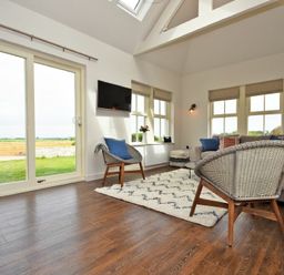 A living room with chairs rug and a television at South View nr Bamburgh in Seahouses