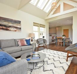 A living room with sofas chairs and a coffee table next to a dining area at South View nr Bamburgh in Seahouses