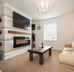A living room with a wall-mounted TV above an electric fireplace a wooden coffee table a beige sofa and wooden shelves at Rivershield in Warkworth
