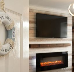 A decorative welcome on board ring hanging on a door with a TV and fireplace in the background at Rivershield in Warkworth