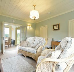 A living room with wicker chairs and a sofa a wooden side table and a TV at Rose Cottage (Elsdon) in Elsdon