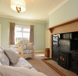 A living room with sofa armchair window and fireplace at Rose Cottage Elsdon