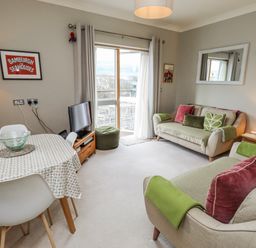 A living room with a sofa and dining table at Cuddy's Holm in Seahouses