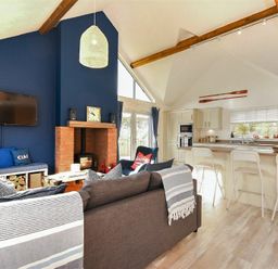 An open living room and kitchen area with a fireplace and blue accent wall at Bowline Cottage in Beadnell