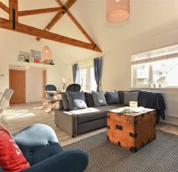 A living area with a gray sofa and wooden chest coffee table near a window at Bowline Cottage in Beadnell