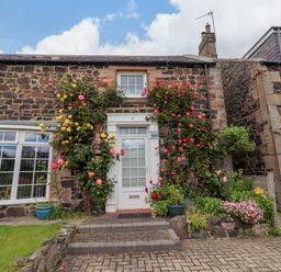 A front view of a cottage with flowers at Coble Cottage in Craster