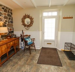 An entryway with a stone wall and a chair at Coble Cottage in Craster