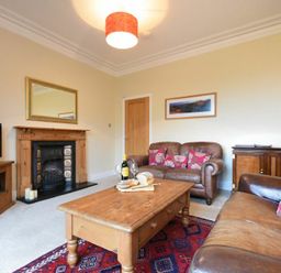 A living room with leather sofas wooden coffee table and fireplace at Sunnybrae Alnmouth