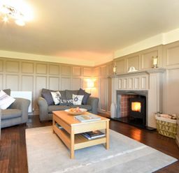A living room with grey sofas wooden coffee table fireplace and television at Mariners House in Alnmouth