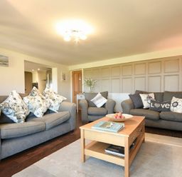 A living room with two sofas and an armchair around a wooden coffee table at Mariners House in Alnmouth
