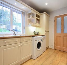 A kitchen with a washing machine under countertop beside a wooden door at Castle View Warkworth