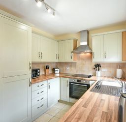 A kitchen with cabinets a stove oven a sink and countertop at Dryden Cottage in Bamburgh