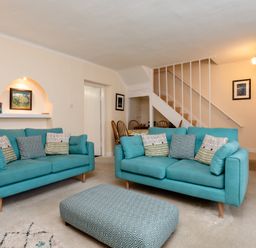A living room with two teal sofas and a patterned ottoman at Percy Cottages No4 in Alnmouth