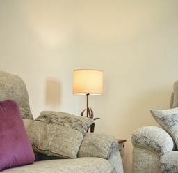A living room with two grey armchairs with cushions and a lamp on a side table between them at The Chevy in Seahouses