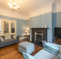 A living room with sofas a fireplace and a television at Nettie's View in Amble