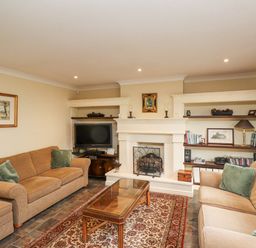 A living room with two sofas a coffee table a fireplace a television and shelves at Rokeby in Bamburgh