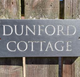 A nameplate reading Dunford Cottage on a wooden fence in Bamburgh