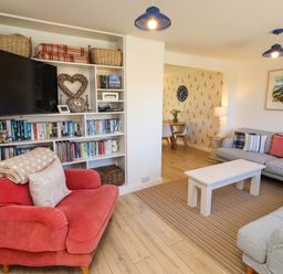 A living room with a television and bookshelves at Dunford Cottage Bamburgh