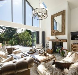 A living room with leather sofas a wooden coffee table a fireplace and large windows at Marmalade Cottage in Seahouses