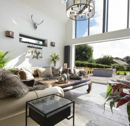 A living room with sofas cushions a coffee table and large windows opening to a garden at Marmalade Cottage in Seahouses