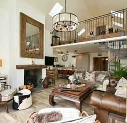 An open living room with a fireplace wooden coffee table sofas armchairs and a mezzanine at Marmalade Cottage in Seahouses