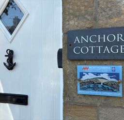 A door with a nameplate and a sign at Anchor Cottage in Seahouses