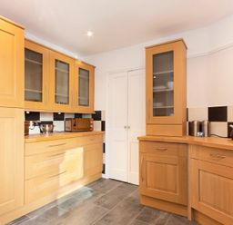 A kitchen with wooden cabinets a microwave kettle and toaster on the countertop at Church View in Bamburgh