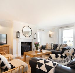 A living room with black leather sofas a wooden coffee table a fireplace and a television at Cargoes in Craster