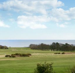 A golf course with trees near the shore and the sea in the background at Viewpoint in Alnmouth